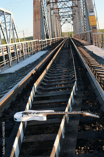 white electric guitar on the railroad tracks and stones © alexkich