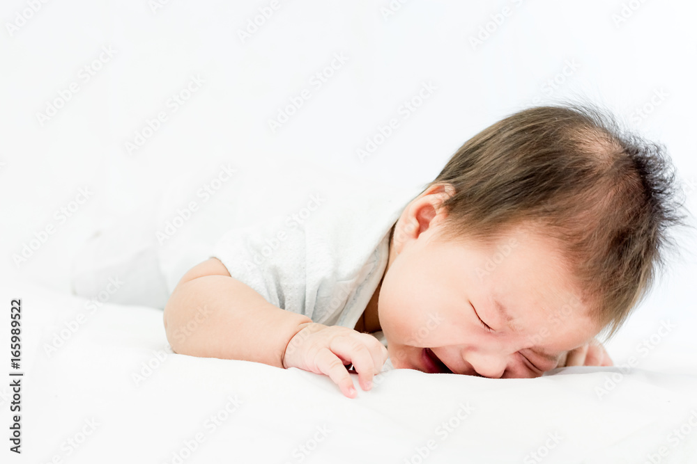 Portrait of a little adorable infant baby girl lying on back on the bed and cry Portrait of a little adorable infant baby girl lying on back on the bed and cry