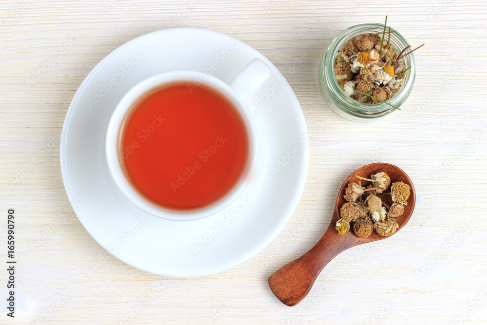 Tea with chamomile in a jar and a wooden spoon