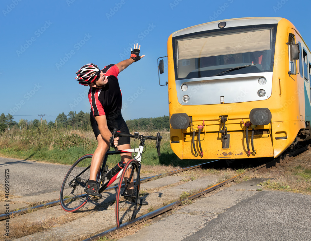 Fototapeta premium Unhappy cyclist has trouble on the railway crossing on Which the train is coming. The train goes to the cyclist stuck in the tracks. Accident on railway.