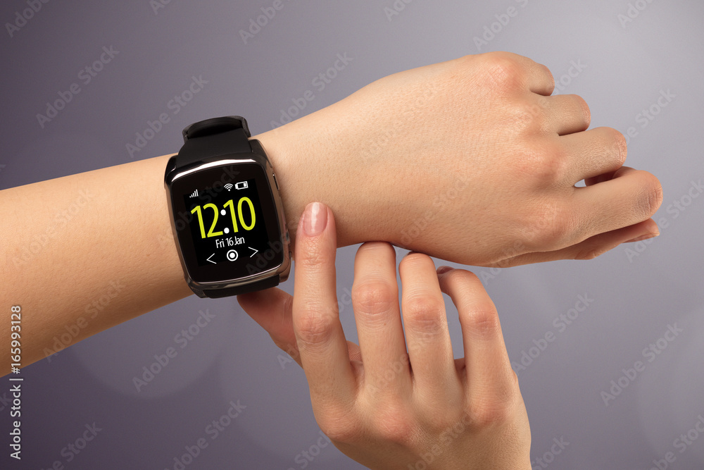 Fototapeta premium Female hand wearing and pressing smartwatch