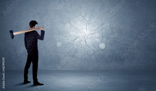 Business man hitting wall with a hammer