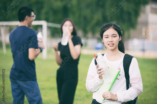 Asian Group of students holding water bottle on the campus lawn