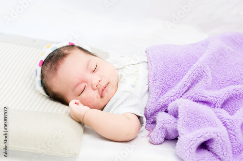 Portrait of sleeping baby  lying on a bed with hat