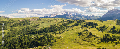 Aerial drone landscape of the meadows at high altitudes, forming gentle hills. Marmolada in the background. Dolomites, Alta Badia, Sud Tirol, Italy