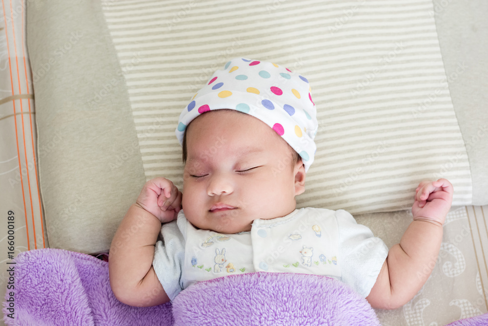 Portrait of sleeping baby lying on a bed with hat Portrait of sleeping baby lying on a bed with hat