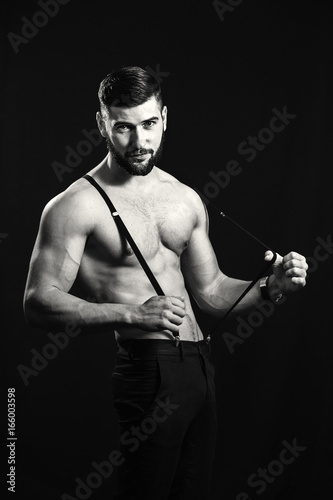 Young handsome muscular man with a beard, posing on a black background