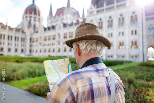 Canvas Print Senior tourist man in hat searching for destination on map