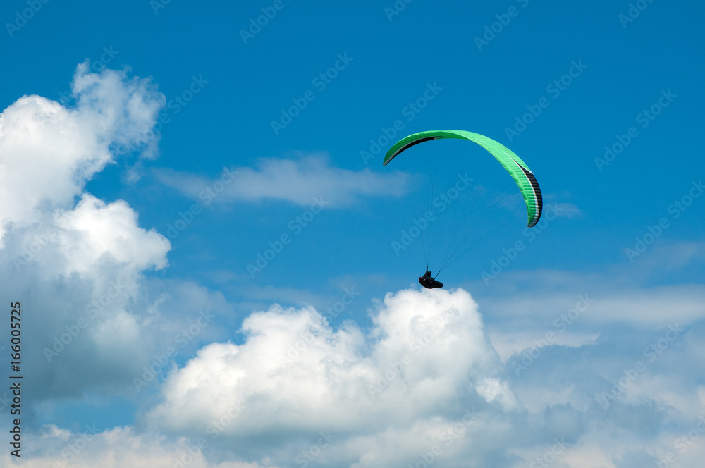 Alone paraglider fly in the sky in the sunny day.
