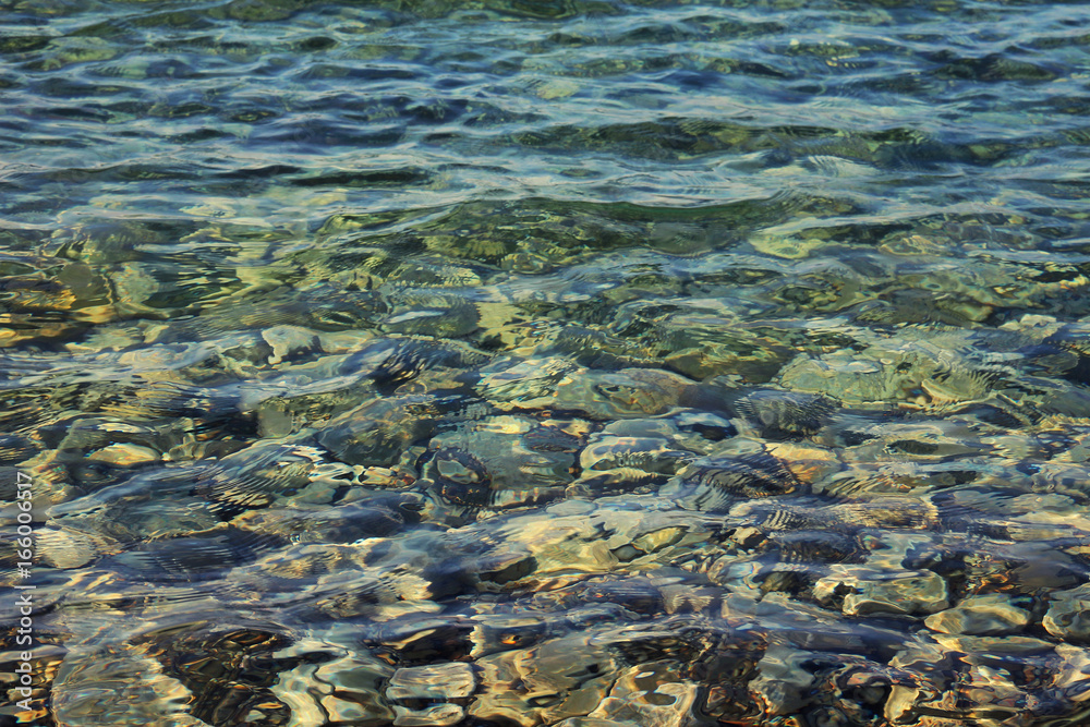 Colorful pebbles under blue sea shallow water