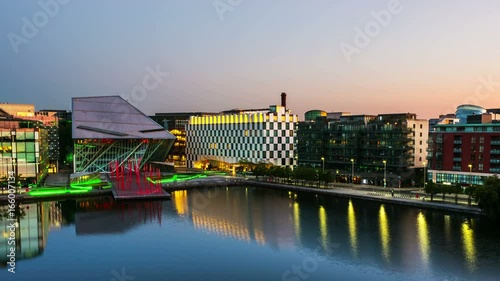 Dublin, Ireland. Aerial view of Grand Canal docks in Dublin, Ireland at sunrise. Empty streets and illuminated modern buildings, colorful clear sky. Time-lapse from night to day