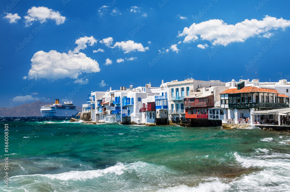 Little Venice, Mykonos island, Greece. Colourful buildings and balconies near the sea and a large white cruise ship.