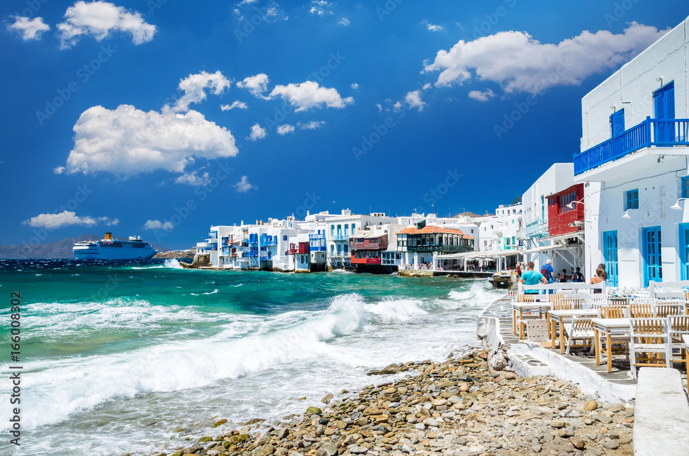 Little Venice, Mykonos island, Greece. Colourful buildings and balconies near the sea and a large white cruise ship.