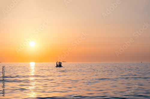 Scenic sunset over the Adriatic Sea with a silhouette of people on a boat. © allasimacheva