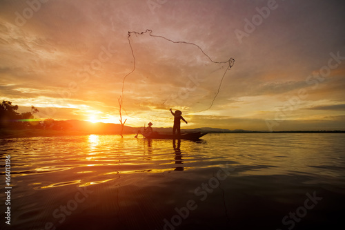 Silhouette Fisherman Fishing by using Net on the boat in Thailand