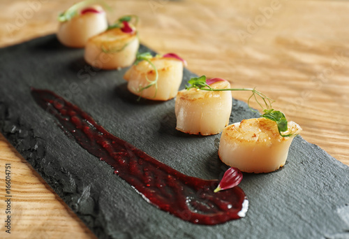 Slate plate with delicious scallops on table