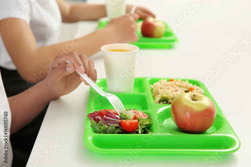 School boy eating delicious food at table