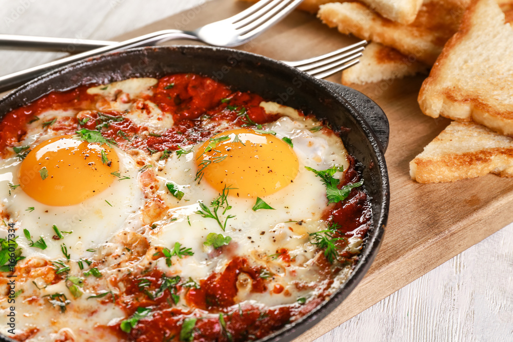 Frying pan with eggs in purgatory on cutting board Frying pan with eggs in purgatory on cutting board