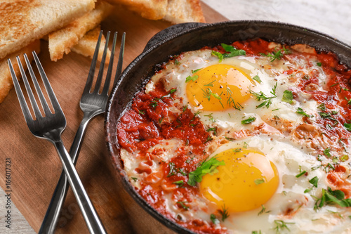 Photos Frying pan with eggs in purgatory on cutting board