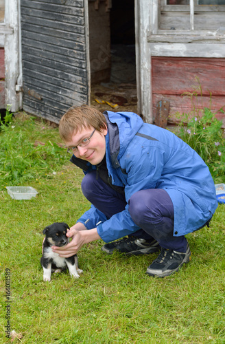 Young man playing with small monthly puppy of Lapland Reindeer dog photo