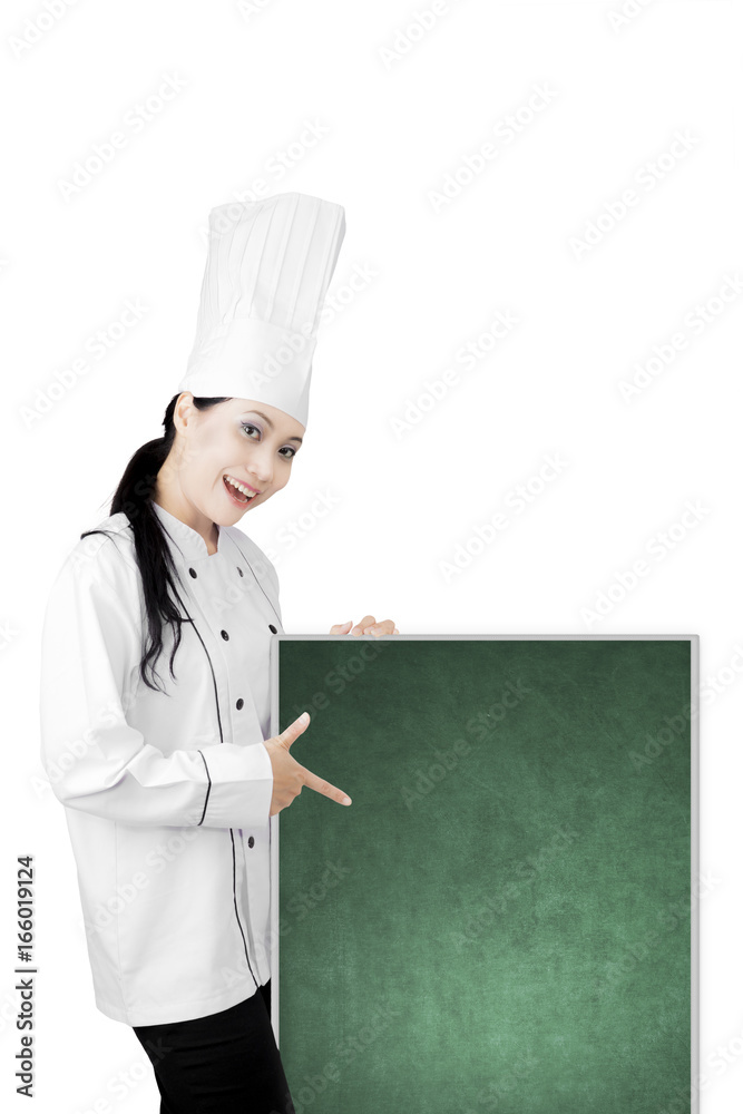 Beautiful chef pointing a blank chalkboard Beautiful chef pointing a blank chalkboard
