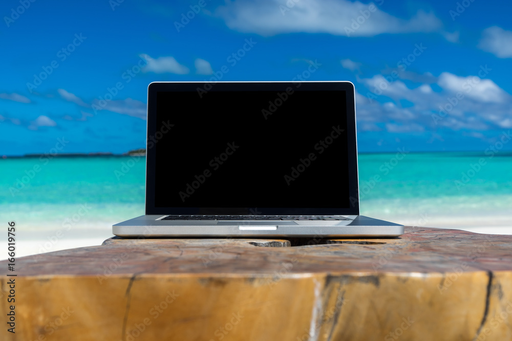 laptop blank screen on wooden desk with beach. relax concept.