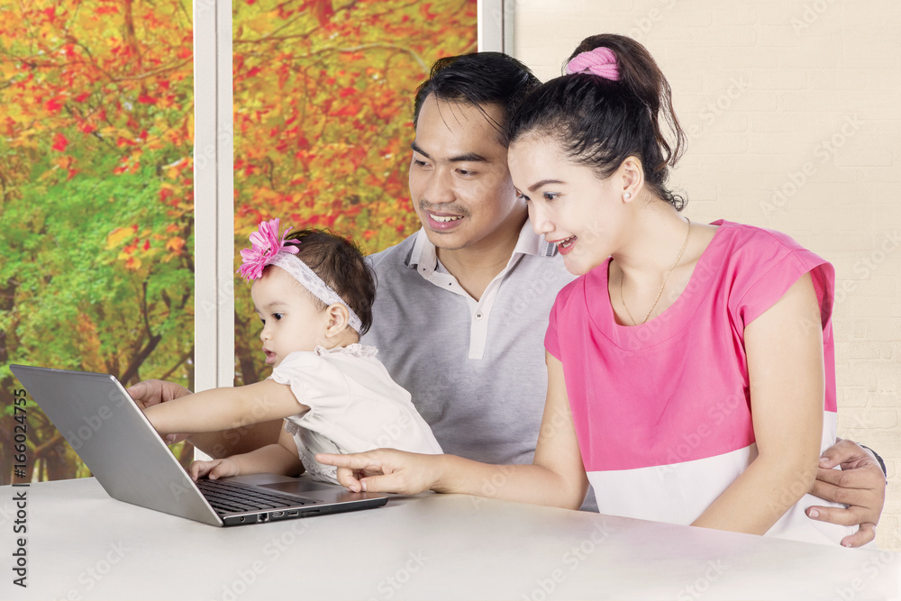 Smiling parents and child looking at laptop Smiling parents and child looking at laptop