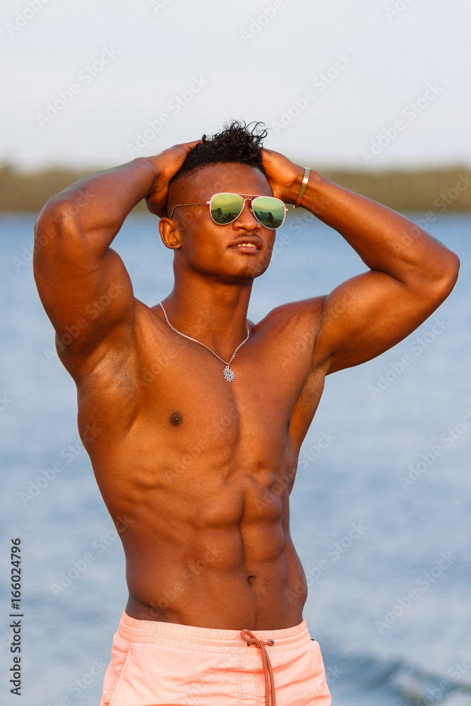 A young athletic beautiful guy with a muscular body. A black sports man is  practicing on