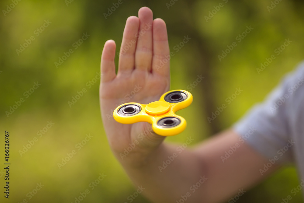 The boy holds a yellow fidget hand spinner The boy holds a yellow fidget hand spinner