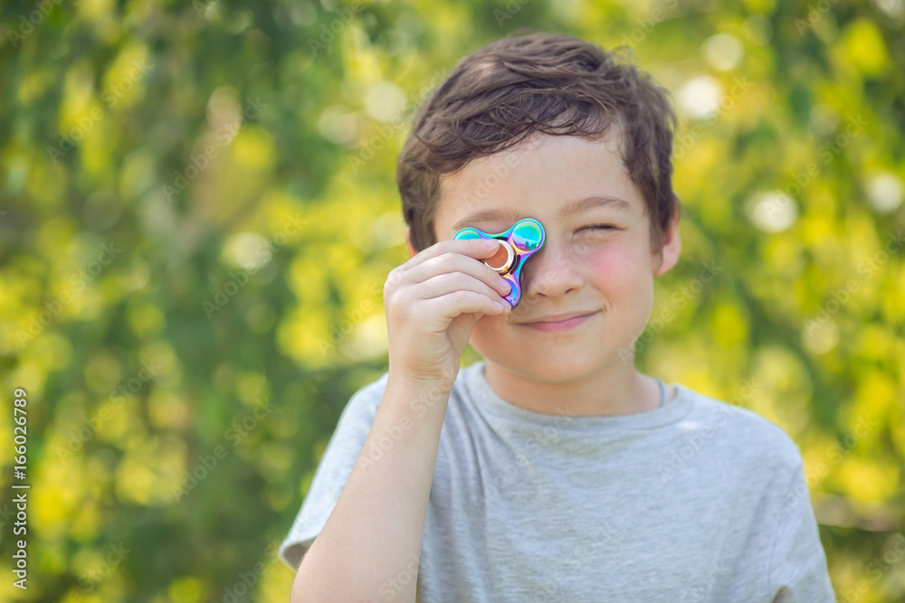 The boy holds a rainbow fidget hand spinner The boy holds a rainbow fidget hand spinner