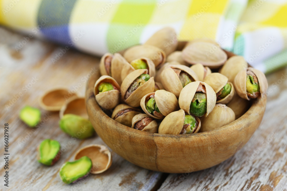 Healthy snack: pistachio nuts in wooden bowl, closeup