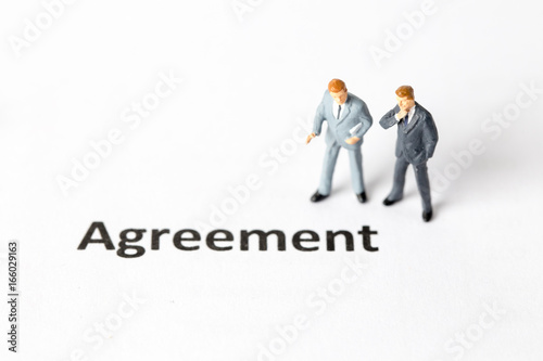 Miniature model of businessman standing with agreenent wording. People with agreement concept.