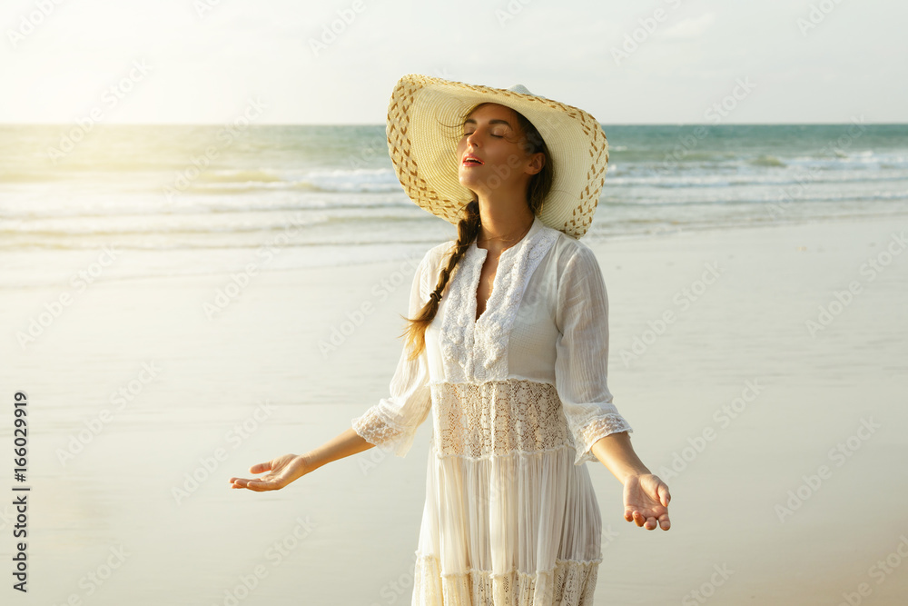 Portrait of beautiful young woman with broad-brimmed hat on the beach