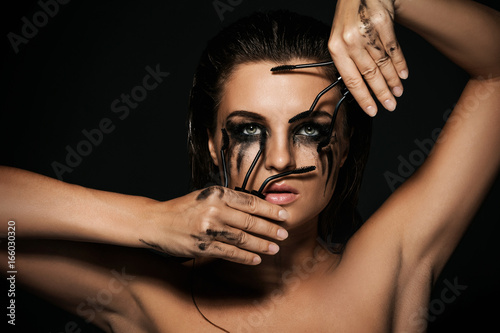 Woman with smudges of makeup on her face and broken mascara brushes photo
