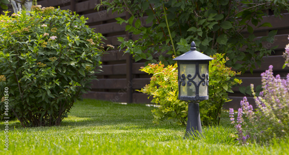 Garden lighting - lights on the solar battery on a green lawn next to a paved path Garden lighting - lights on the solar battery on a green lawn next to a paved path