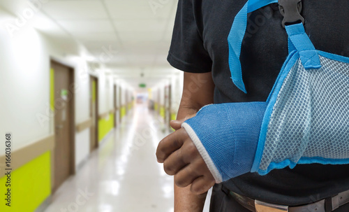 Man's arm in cast and sling with blurred hospital background