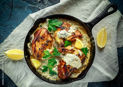 Schilderij op canvas Creamy chicken fellets supremes in mushroom sauce with parsley In rustic cast iron skillet
