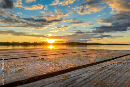 Wooden pier with water at sunset and beautiful bright clouds