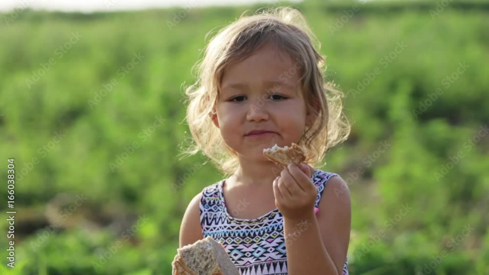 Portrait of little girl eating homebaked bread on the field of organic eco farm Portrait of little girl eating homebaked bread on the field of organic eco farm