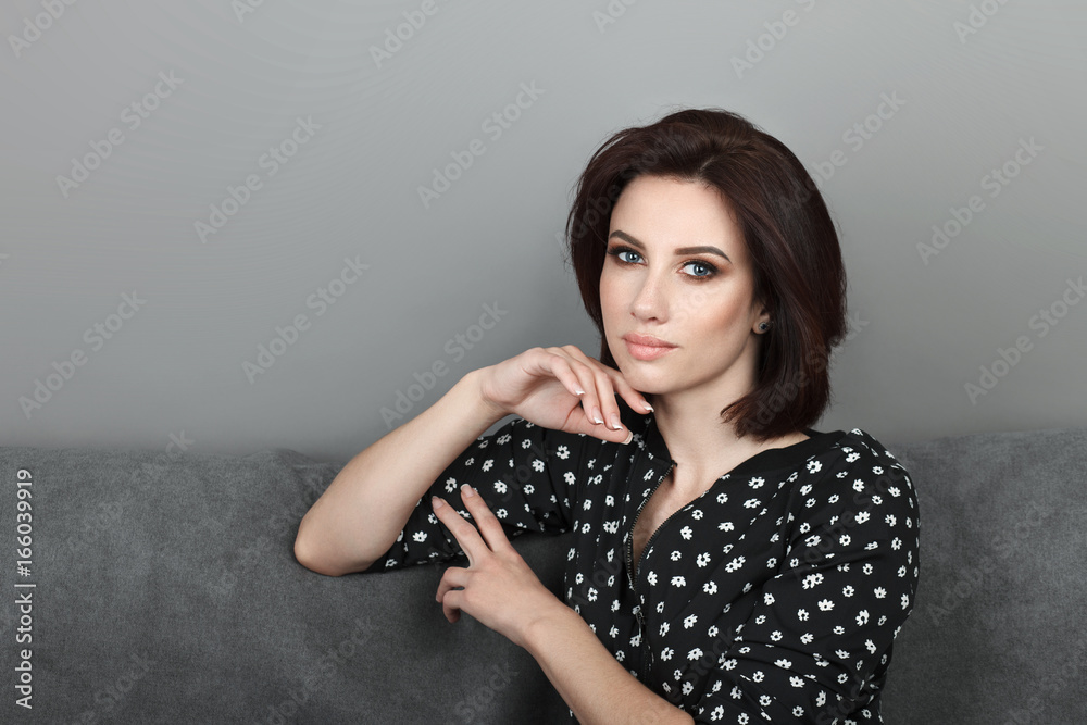 Beauty portrait sporty adult adorable fresh looking brunette woman gorgeous makeup bob hairdo posing grey sofa wall showing emotion and facial expression concept.