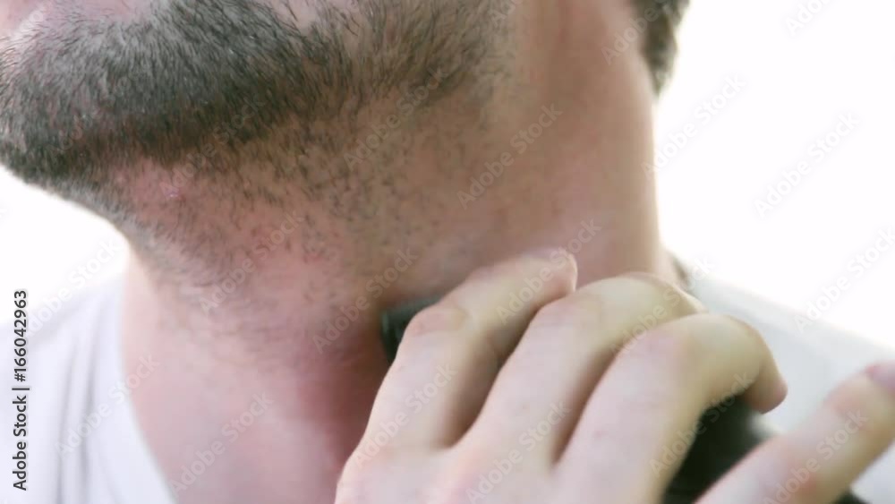 Young man shaves himself in the morning in front of the mirror