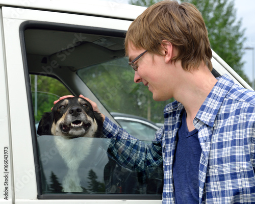 Young man caresses dog (Lapland Reindeer dog, Reindeer Herder, lapinporokoira (Finnish), lapsk vallhund (Swedish) in car photo