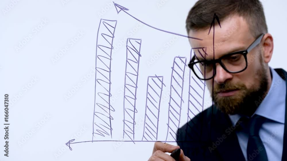 Man draws various growth charts, calculating prospects for success in a modern glass office Man draws various growth charts, calculating prospects for success in a modern glass office