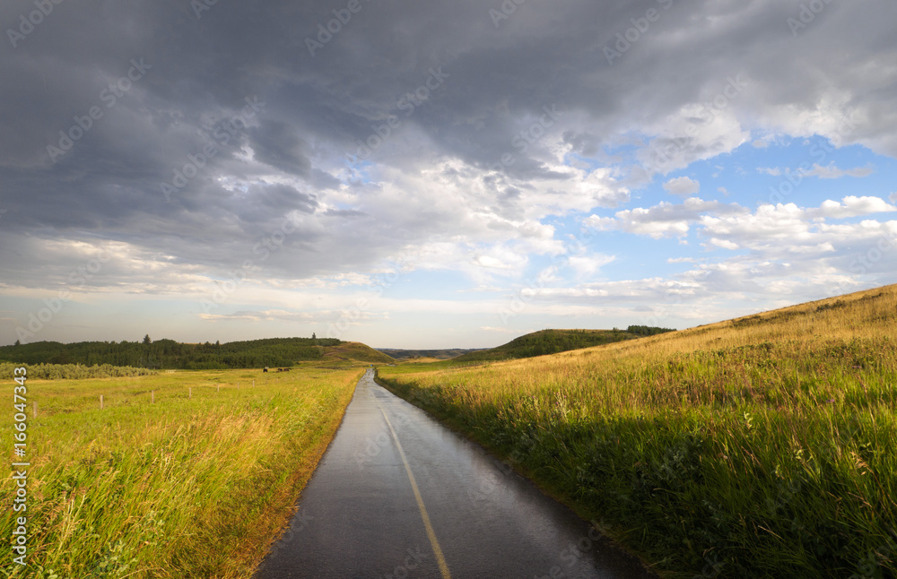 Rainy Bike path through the countryside prairie fields and rolling hills with rain clouds