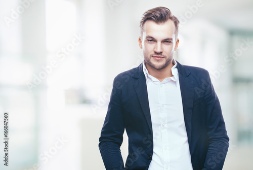 Handsome stylish young man in shirt looking at the camera. Office worker. Business decisions. Beautiful light background