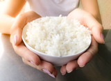 Hand of woman holding a white rice in the bowl.