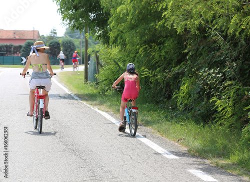 Family with mom and young daughter pedal on the paved road