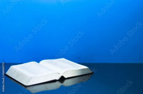 Bible and a crucifix on a glass table. Beautiful blue background.Religion concept. photo