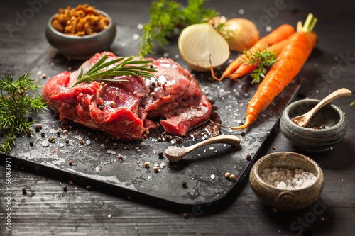 Deer or venison roast, traditional finnish food, rosvopaisti, with Chanterelle fungus, Sea salt, red, green, white pepper and coriander in clay pots on an old black rustic table. 
 photo