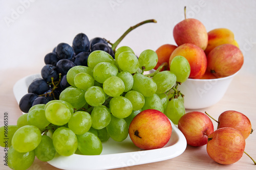 A bunch of grapes, apples on a white plate